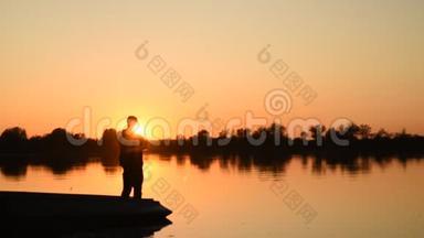 在美丽的日落中享受钓鱼的人剪影。
